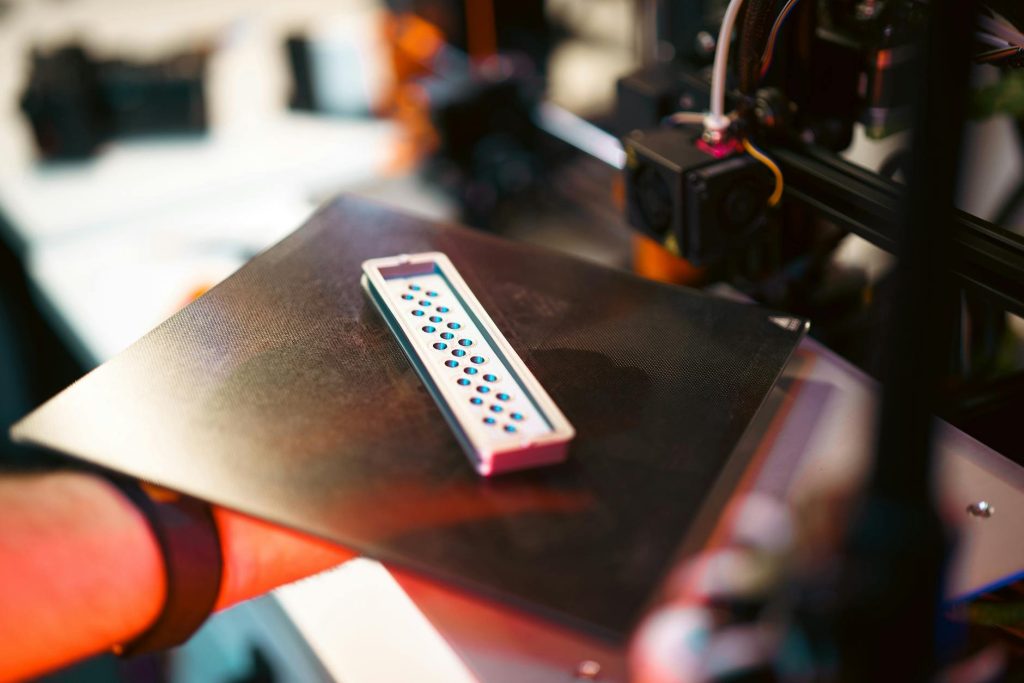 A team of professional engineers and designers collaborating over 3D printed components on a worktable in a well-equipped Kenyan production facility